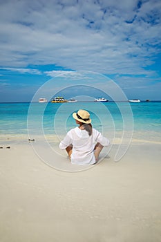 Young beautiful woman in a hat on a deserted tropical beach. Relaxation concept