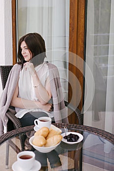 Young beautiful woman having breakfast on a cozy terrace