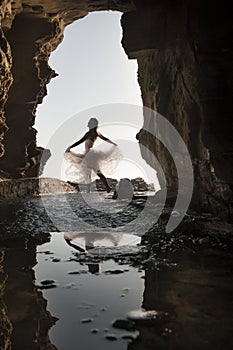 Young beautiful woman having fun dancing under rock archway