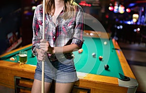 Young beautiful woman having fun and playing billiard in a club