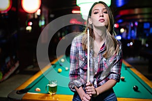 Young beautiful woman having fun and playing billiard in a club