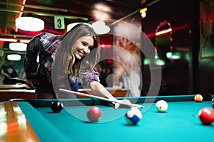 Young beautiful woman having fun and playing billiard in a club