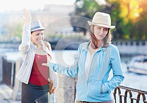 Young beautiful woman having quarrel with her friend in the city