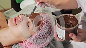 Young beautiful woman having spa procedure on her face. Chocolate spa. Chocolate wrap. Close-up