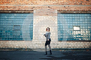 Young beautiful woman with headphones and smartphone in hand in mirrored sunglasses, a black leather jacket, black jeans danc
