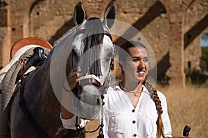 Young and beautiful woman with her horse, resting with him, caressing him, happy in the countryside. Concept horse riding, animals