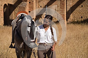 Young and beautiful woman with her horse, resting with him, caressing him, happy in the countryside. Concept horse riding, animals