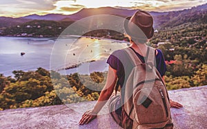 Young beautiful woman hipster traveler looking at sunset and beautiful seascape with a lookout point. Freedom, travel, vacation