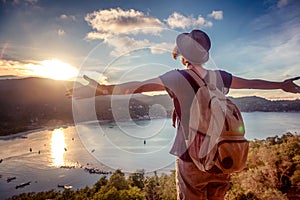 Young beautiful woman hipster traveler looking at sunset and beautiful seascape with a lookout point. Freedom, travel, vacation