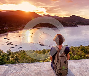 Young beautiful woman hipster traveler looking at sunset and beautiful seascape with a lookout point. Freedom, travel, vacation