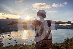 Young beautiful woman hipster traveler looking at sunset and beautiful seascape with a lookout point. Freedom, travel, vacation