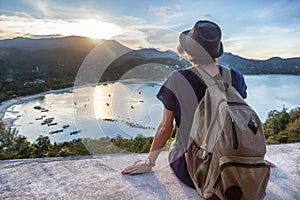 Young beautiful woman hipster traveler looking at sunset and beautiful seascape with a lookout point. Freedom, travel, vacation