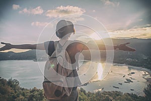 Young beautiful woman hipster traveler looking at sunset and beautiful seascape with a lookout point. Freedom, travel, vacation