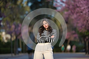 Young and beautiful woman, Hispanic, brown hair, with striped sweater, linen pants, arms crossed, independent and empowered, in