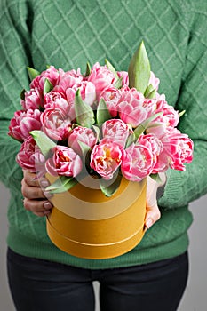 Young beautiful woman holding a bouquet of tulips in a gift box. pink colors in one box or bouquet. Present on March 8
