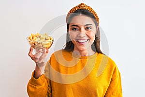 Young beautiful woman holding bowl with macaroni pasta over isolated white background with a happy face standing and smiling with