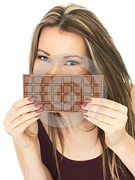 Young Beautiful Woman Holding a Chocolate Bar Over Mouth