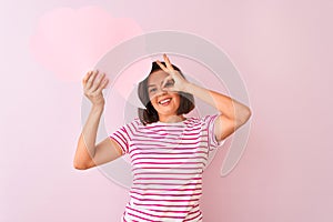Young beautiful woman holding cloud speech bubble standing over isolated pink background with happy face smiling doing ok sign