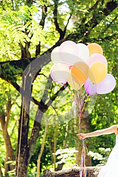 Young beautiful woman holding colorful air balloons in the park.  Relaxation on international womens day