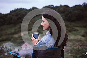 Young beautiful woman holding a cup of coffee with happy and smiling while sitting at outdoor,Travel concept