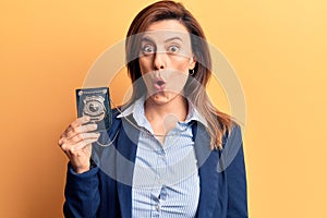 Young beautiful woman holding detective badge scared and amazed with open mouth for surprise, disbelief face