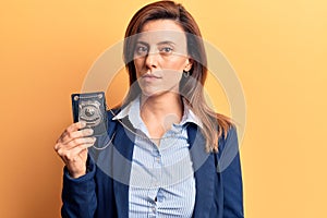 Young beautiful woman holding detective badge thinking attitude and sober expression looking self confident