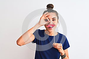 Young beautiful woman holding fanny party mustache over isolated white background with happy face smiling doing ok sign with hand