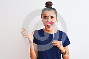 Young beautiful woman holding fanny party mustache over isolated white background very happy and excited, winner expression