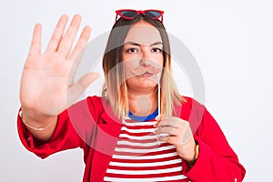 Young beautiful woman holding fanny party mustache standing over isolated white background with open hand doing stop sign with