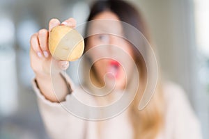 Young beautiful woman holding fresh potato at home scared in shock with a surprise face, afraid and excited with fear expression