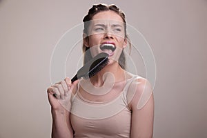 Young beautiful woman holding hairbrush pretending to be singer