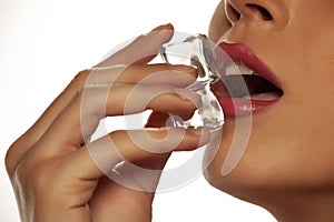 Young beautiful woman holding ice cube in her mouth