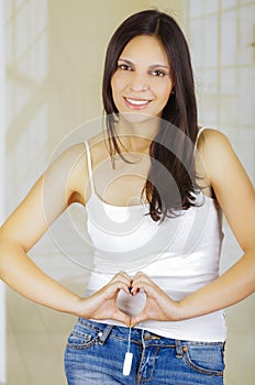 Young beautiful woman holding a menstruation cotton tampon with both hands and doing a heart sign with her hands