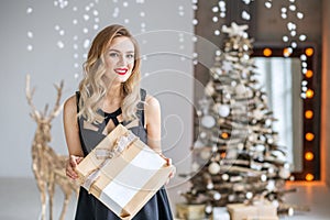 A young beautiful woman is holding a present and smiling. Concept of Happy Christmas and New Year, winter, party