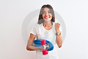 Young beautiful woman holding skate standing over isolated white background screaming proud and celebrating victory and success