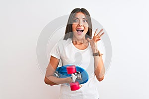 Young beautiful woman holding skate standing over isolated white background very happy and excited, winner expression celebrating