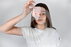 Young beautiful woman holding slice of ham near her face loking hungry isolated white background