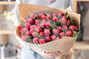 Young beautiful woman holding a spring bouquet of red tulips in her hand. Bunch of fresh cut spring flowers in female