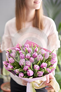 Young beautiful woman holding a spring bouquet of yellow tulips in her hand. Bunch of fresh cut spring flowers in female
