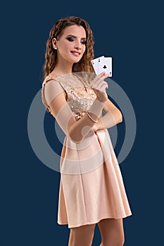 Young beautiful woman holding the winning combination of poker cards on dark blue background. Two aces