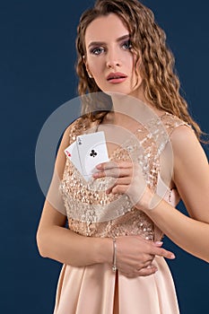 Young beautiful woman holding the winning combination of poker cards on dark blue background. Two aces
