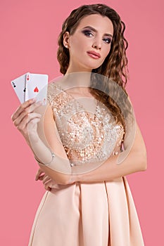 Young beautiful woman holding the winning combination of poker cards on pink background. Two aces