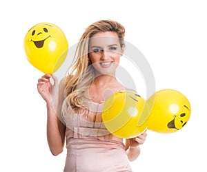 Young beautiful woman holding yellow smiley balloons, valentine'