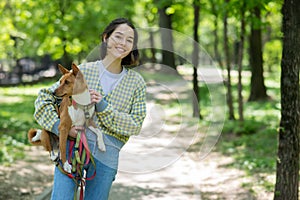 A young beautiful woman holds a dog in her arms for a walk. non-barking african basenji dog.