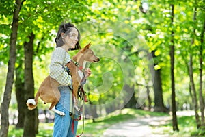 A young beautiful woman holds a dog in her arms for a walk. non-barking african basenji dog.