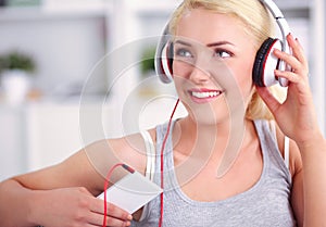 Young beautiful woman at home sitting on sofa and listening music