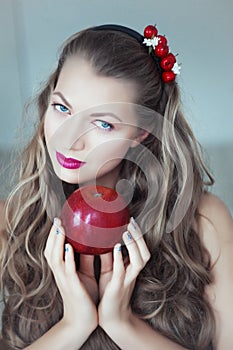 Young beautiful woman with hoop in hair and apple in hands