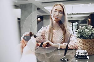 Young beautiful woman hotel guest paying for her stay with credit card at front desk