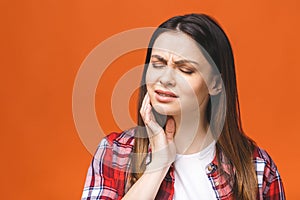 Young beautiful woman isolated on orange background suffering from severe toothache, feeling pain so strong that she is pressing