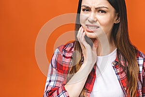 Young beautiful woman isolated on orange background suffering from severe toothache, feeling pain so strong that she is pressing